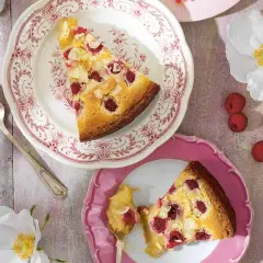 En ljus kladdkaka med hallon och mandel, serverad på vackra fat. En perfekt sommardessert.
