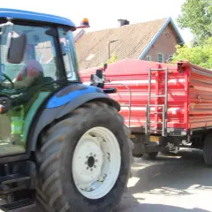 Kierowca w kabinie traktora z przyczepą. Czy na kat B można jeździć ciągnikiem z przyczepą? To pytanie nurtuje wielu rolników.