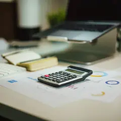 Kalkulator na biurku obok laptopa i wykresów. Czas policzyć, **brutto co to** znaczy w tym kontekście.