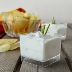 Salsa yogurt cremosa, guarnita con erba cipollina, pronta per accompagnare patatine croccanti.
