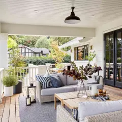 Cozy backyard makeover with a covered porch, outdoor sofa, coffee table, and fireplace.
