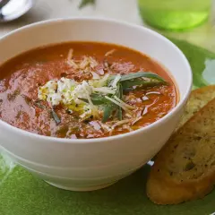 Aksamitna zupa solferino z serem feta i grzankami czosnkowymi na zielonym talerzu.