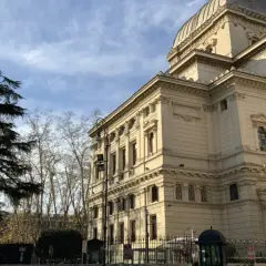 Grande Sinagoga e alberi nel quartiere ebraico di Roma, sotto un cielo azzurro con nuvole.