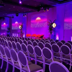 Un auditorium à Paris, baigné de lumières violettes, prêt pour un événement futuriste. Des rangées de chaises attendent les invités.