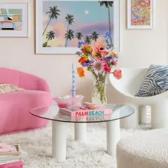 Ein Wohnzimmer im **danish pastel** Stil mit pinkem Sofa, bunten Blumen und Kunstwerken.