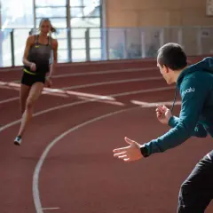 Trener biegania instruuje zawodniczkę na bieżni.