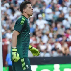 Wojciech Szczęsny w zielonej koszulce bramkarskiej Juventusu stoi przy bramce.