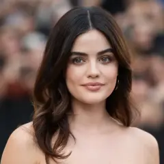 Mujer con media melena pelo liso y fino, ojos verdes y labios rosados, sonríe levemente.