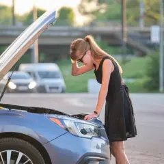 Donna preoccupata guarda il motore della sua auto, il motore diesel gira ma non parte.