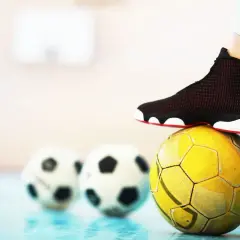 Stopa na żółtej piłce, w tle dwie białe. To pytanie: futsal co to?