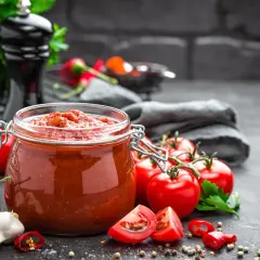 Słoik domowego sosu po polsku, obok świeże pomidory, czosnek i papryczki chili.