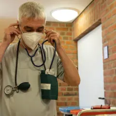 Mann mit Stethoskop und Maske im Flur, bereit für die Umschulung Gesundheits- und Krankenpfleger.