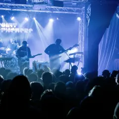 Un groupe joue sur scène sous des lumières bleues. Découvrez les **upcoming concerts in Paris** !