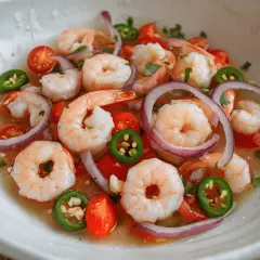Un refrescante ceviche de gambas con tomate, cebolla morada y jalapeño en un cuenco blanco.