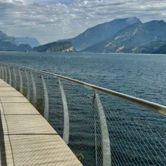 Drewniana promenada nad jeziorem Garda, z widokiem na góry i żaglówki. Idealne miejsce na spacer po mieście.
