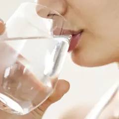 Une femme boit un verre d'eau. Une question importante pour les jeunes mamans : quelle eau boire allaitement ?