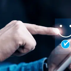 Dłoń wybiera uśmiechniętą buźkę na ekranie tabletu, oceniając jakość obsługi klienta (cx).