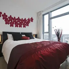 Elegancka, bordowa sypialnia z kwitnącymi wiśniami na ścianie i widokiem na miasto.