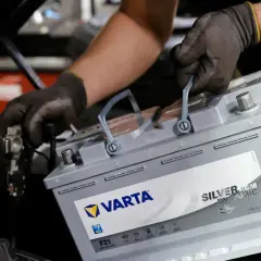 Mechanik w rękawiczkach wymienia akumulator Varta Silver AGM Dynamic, dbając o jego żywotność.