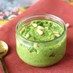 Un frasco de pesto casero, perfecto para tu próxima pasta al pesto receta, adornado con piñones.