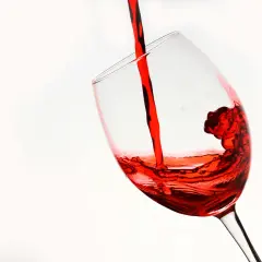 Czerwone wino, niczym reserva especial, wylewa się do kieliszka, tworząc wirujące fale.