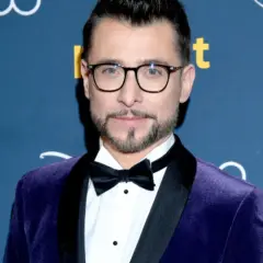 Kacper Kuszewski w fioletowym aksamitnym smokingu z czarną muszką. Wygląda elegancko, jakby wybierał się na galę, gdzie może spotkać swoją żonę.
