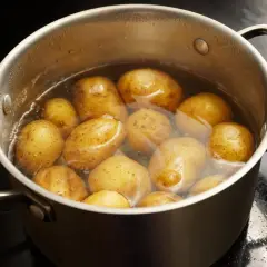 Ein Topf mit vielen Kartoffeln, die in Wasser kochen. Sind Kartoffeln gesund? Ja, sie sind eine gute Quelle für Vitamine und Mineralstoffe.