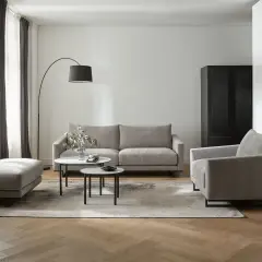 Nowoczesny salon z dwiema sofami, fotelem i pufą. W centrum dwie okrągłe ławy.