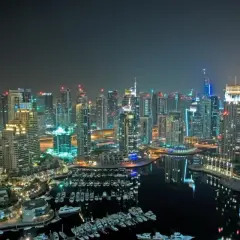 Widok nocą na drapacze chmur i przystań jachtową w Dubaju.
