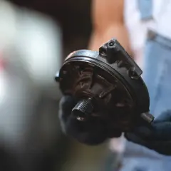 Mechanik w rękawiczkach trzyma element układu kierowniczego – serwo.
