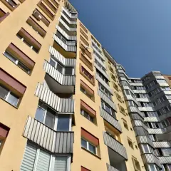 Żółty blok mieszkalny z balkonami, typowe mieszkanie komunalne, pod błękitnym niebem.