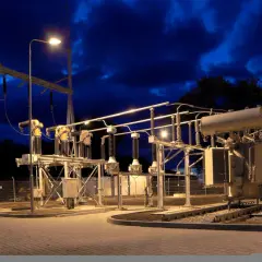Nocna iluminacja podstacji trakcyjnej z transformatorem i izolatorami.