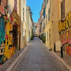 Kolorowa uliczka z brukowaną nawierzchnią, ozdobiona dynamicznym street art graffiti na ścianach budynków.