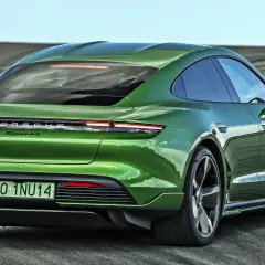 Zielony Porsche Taycan 4S z polskimi tablicami rejestracyjnymi PO-1NU14 na tle pustej drogi.