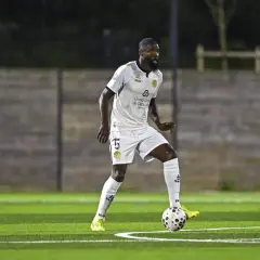 Joueur de football en action sur la pelouse du stade Charléty, concentré sur le ballon.