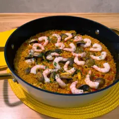 Arroz con gambones y almejas en paellera, listo para disfrutar.