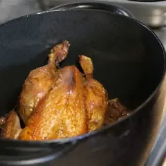 Un poulet rôti doré dans une cocotte. Quel vin rouge avec du poulet ? Un Pinot Noir léger ou un Beaujolais fruité serait parfait.