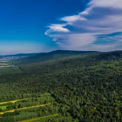 Zielone, leśne góry w okolicach Kielc, z widokiem na pola i błękitne niebo z chmurami.