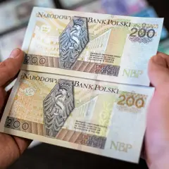 Dwie ręce trzymają banknoty 200 zł. Chcesz wiedzieć, jak wyprostować banknot? Oto rozwiązanie.