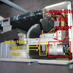 Componentes internos de un aire acondicionado, mostrando el capacitor del motor y el capacitor del fan.