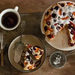 Pyszne ciasto bez glutenu z owocami, posypane cukrem pudrem. Idealne na podwieczorek z herbatą.