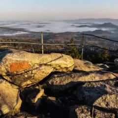 Widok z kamieni na szlaku na Skalnik z Kowar. Mgła spowija doliny, tworząc malowniczy krajobraz.