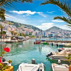 Albania, gdzie najpiękniej! Widok na port z łodziami i kolorowe budynki na wzgórzu.