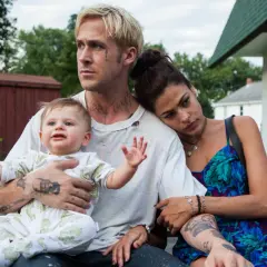 Ryan Gosling barn i famnen, med Eva Mendes vid sin sida. En stund av familjefrid trots omgivningen.