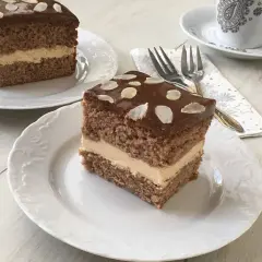 Pyszne ciasto z mascarpone i kajmakiem, polane czekoladą i posypane płatkami migdałów. Idealne na deser.