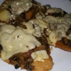 Schab w plastrach pieczony w piekarniku z pieczarkami i serem, danie wygląda apetycznie i jest gotowe do podania.