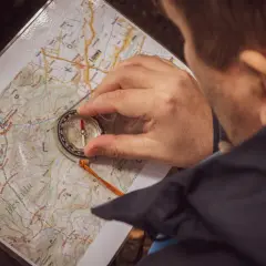 Mężczyzna z kompasem i mapą w Beskidach, przygotowuje się do wyprawy bushcraft a survival.