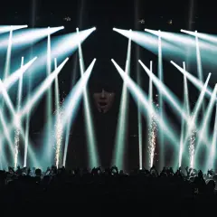 Koncert Apashe w Warszawie: tłum szaleje pod laserami i fajerwerkami, artysta na ekranie.