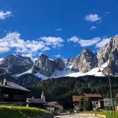 Villaggio alpino con case in legno e montagne innevate sullo sfondo. Un assaggio di cosa vedere in Carnia, tra natura e tradizione.