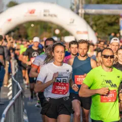 Uczestnicy biegu, realizujący swój plan treningowy maraton, mijają bramę startową.